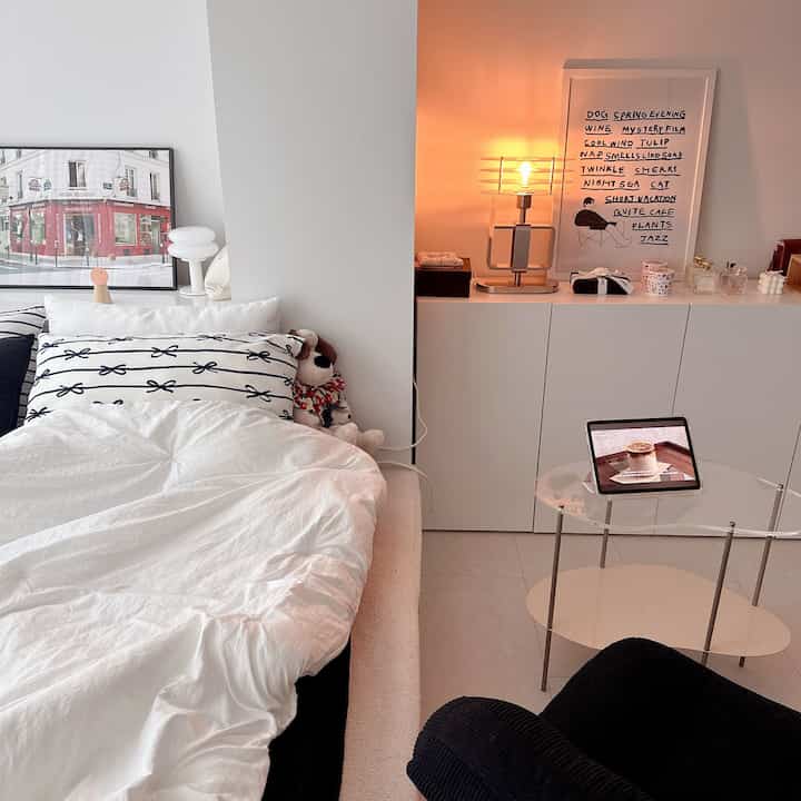 白と黒のモダンな寝室、コーデュロイソファとテーブルランプが配置された雰囲気のある空間