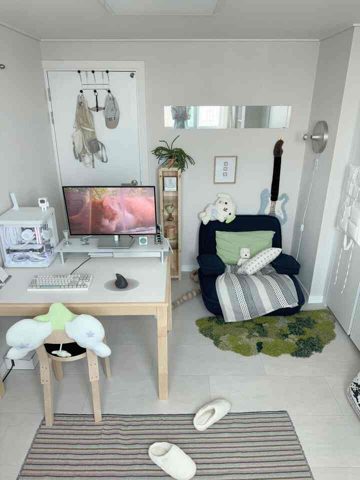 White and natural wood toned home office featuring a desk with computer and a floor chair with cushions in a simple modern style