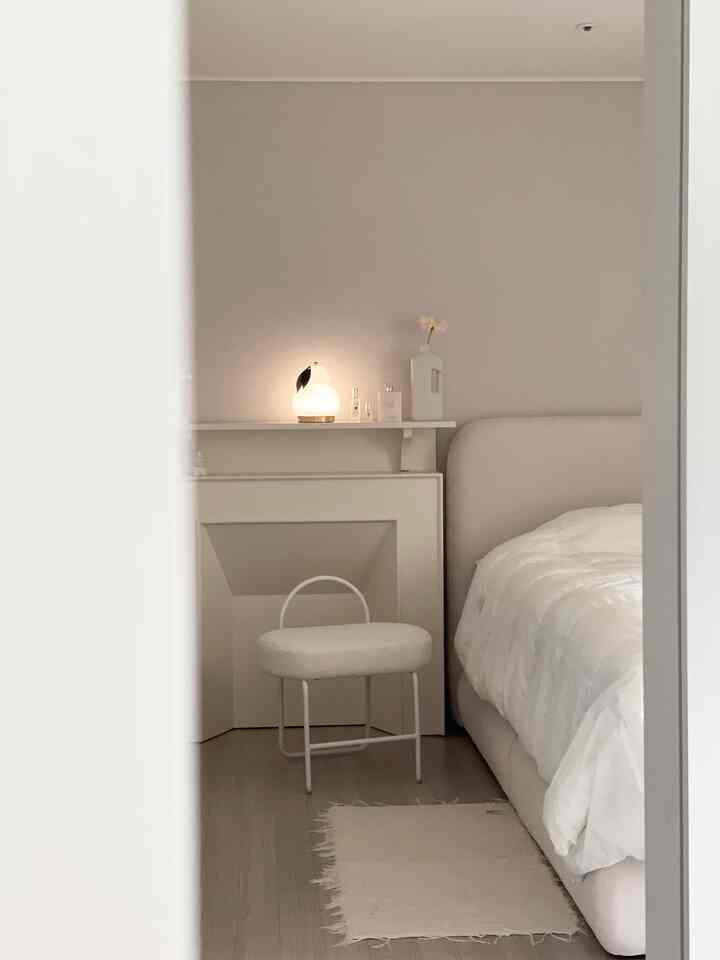 White-toned bedroom featuring a bouclé upholstered stool and sleek furniture creating a calm atmosphere