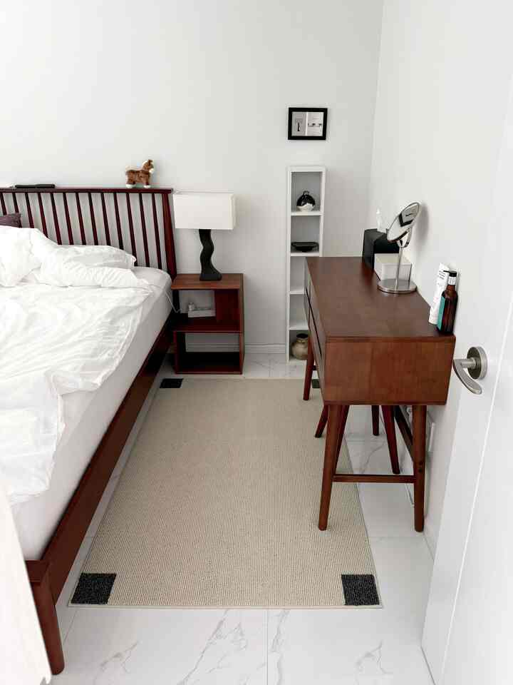 白い壁とタイル床に、木製のベッドフレームと化粧台が配置された整ったモダンな寝室