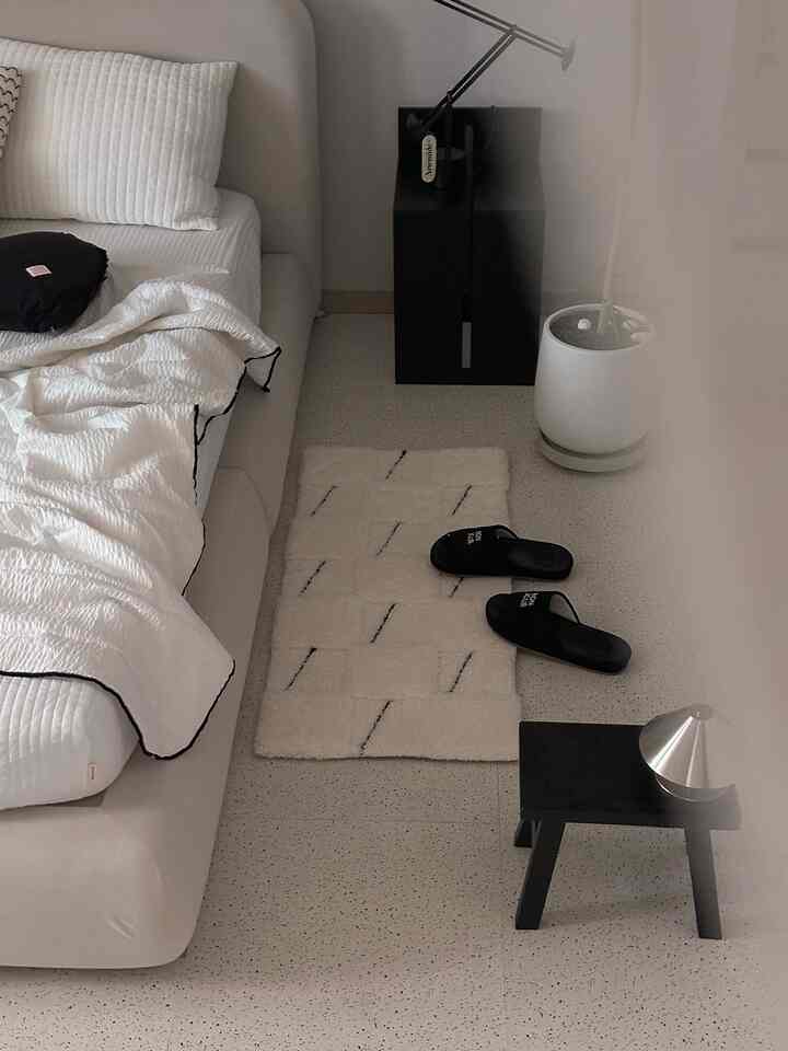 白と黒のトーンのモダンな寝室、シンプルな家具とベッドリネンが配置されたホテルライクなインテリア