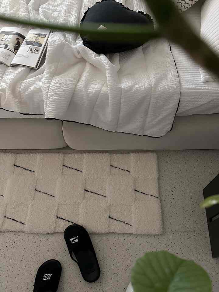 White and beige toned living room featuring sofa with cushions and rug, creating a calm and natural atmosphere