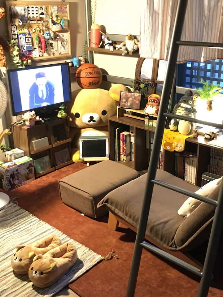 暖かみのあるブラウンと木目調の狭い寝室、リラックマのぬいぐるみと赤ちゃん向けアイテムが配置された居心地の良い部屋の装飾