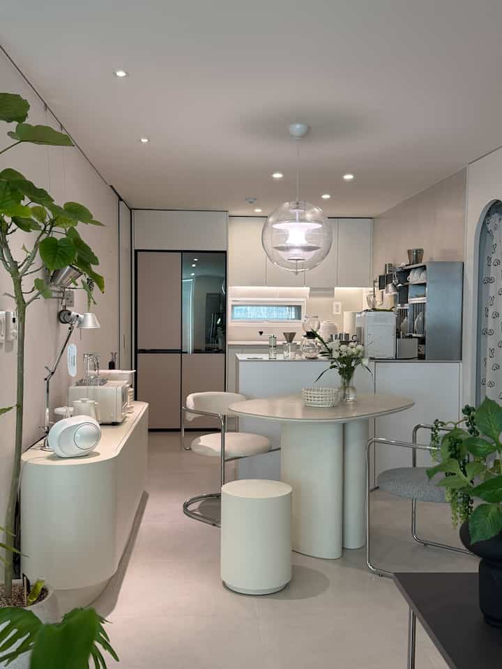 白を基調としたモダンなキッチンスペース、ポーセリンテーブルとダイニングチェアが配された清潔感のあるインテリア