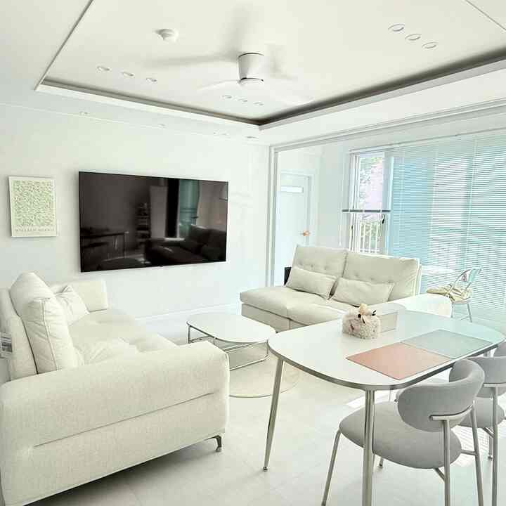 明るく白色を基調としたリビング、2つのソファとダイニングテーブルが配置されたシンプルモダンなインテリア