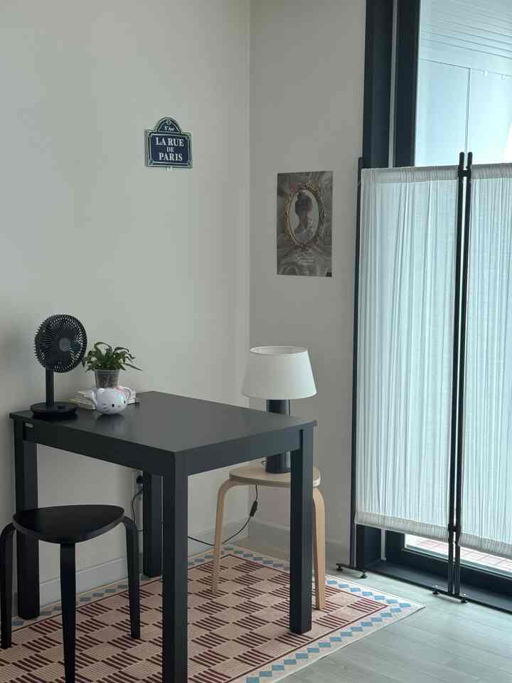 ナチュラルと黒の色調の小さなホームオフィス、黒いスツールと化粧台にテーブルランプが置かれた雰囲気のあるインテリア