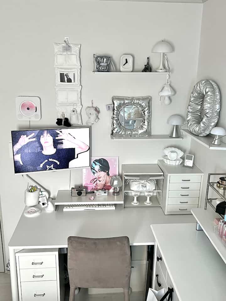 白とシルバーのトーンのホームオフィス、清潔で整理されたデスクとモニター、多様な収納家具と装飾品が配置された雰囲気のあるインテリア