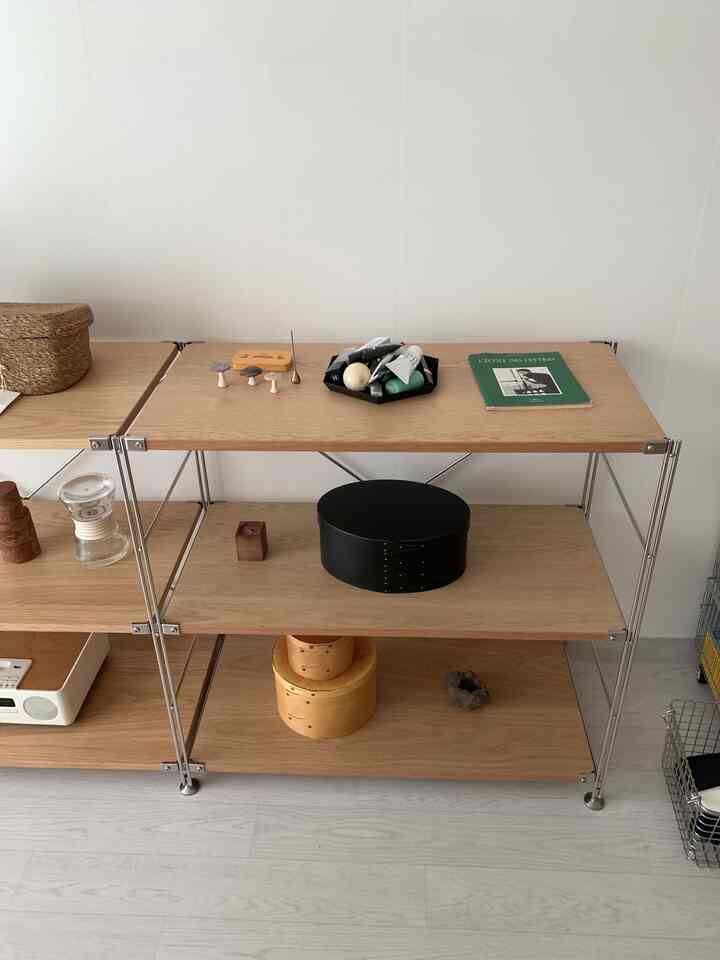 ナチュラルな木目調の棚に様々な小物や収納箱が配置されたシンプルなリビングのインテリア