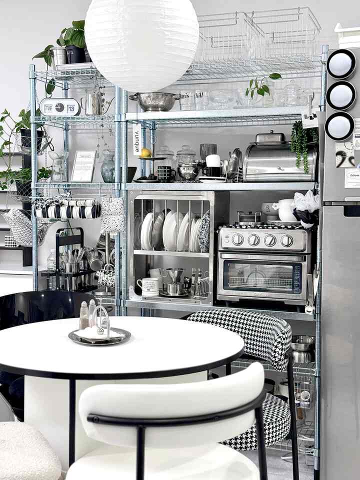 White and black toned kitchen space featuring a round dining table and neatly organized kitchenware with mid-century modern style