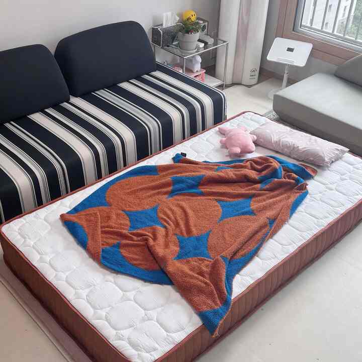 ホワイトとブラウンの色調の子供部屋、ストライプのソファとマットレスが配置されたシンプルな雰囲気のあるインテリア