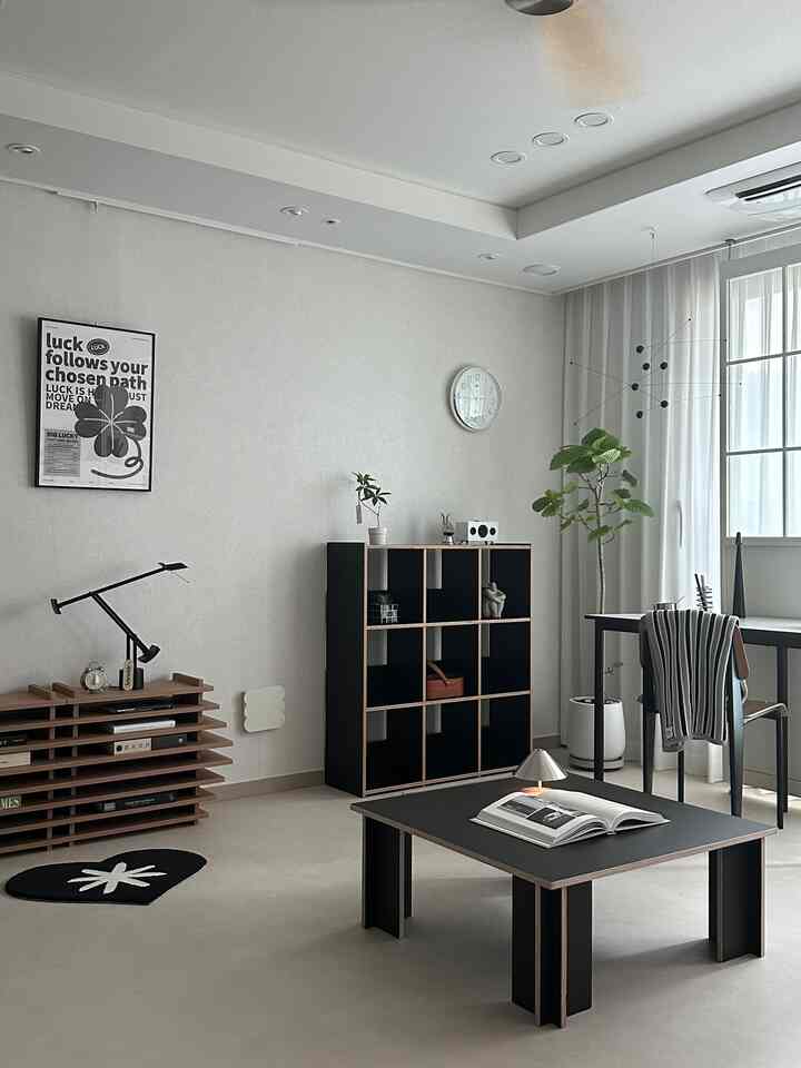 モノトーンと木目調が調和したリビング、ブラックのテーブルと植物が温かみを感じさせるシンプルな雰囲気のインテリア