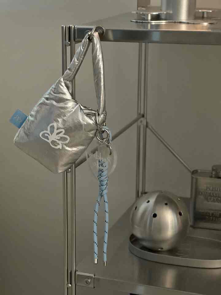 ステンレス製のミニマルな収納棚に小さな銀色のバッグが掛けられたすっきりとした空間