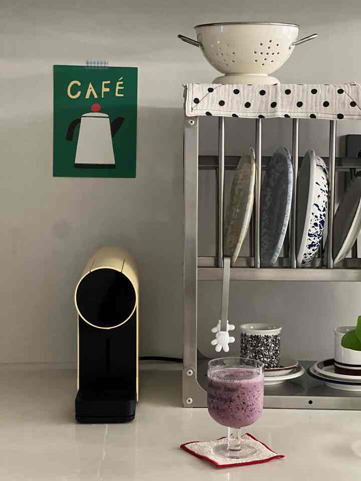 白とナチュラルカラーのキッチン、コーヒーマシンと皿ラック、コースターの上に紫色のドリンクがある雰囲気のあるおうちカフェ