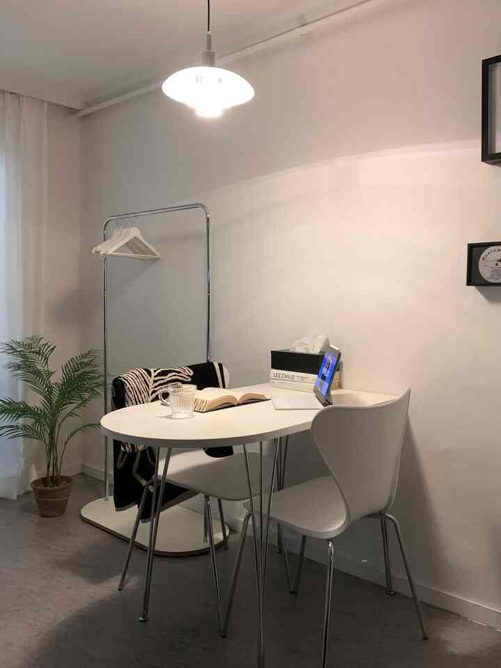 White-toned compact dining room featuring simple furniture, chrome rack, and natural plant for a minimalist space