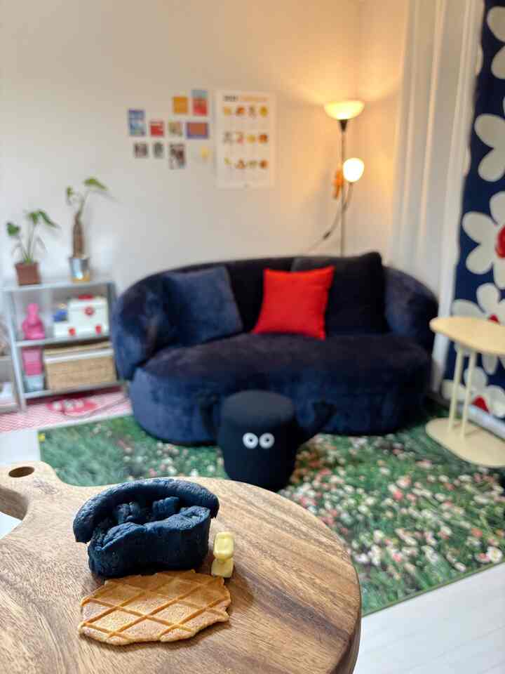 ナチュラルな木目調とネイビーのソファがある居心地のよいリビング、花柄のラグとフロアランプが配置された雰囲気のある空間