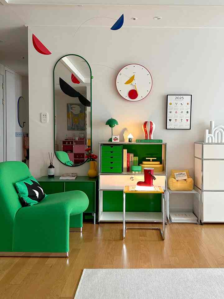 Vivid green and white toned living room featuring a mobile, clock, rug, and modern furniture, creating a bright and fresh atmosphere