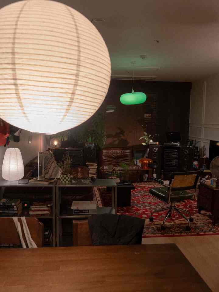 Brown and red toned living room featuring leather sofas, vintage furniture, and multiple ambient lamps creating a cozy atmosphere