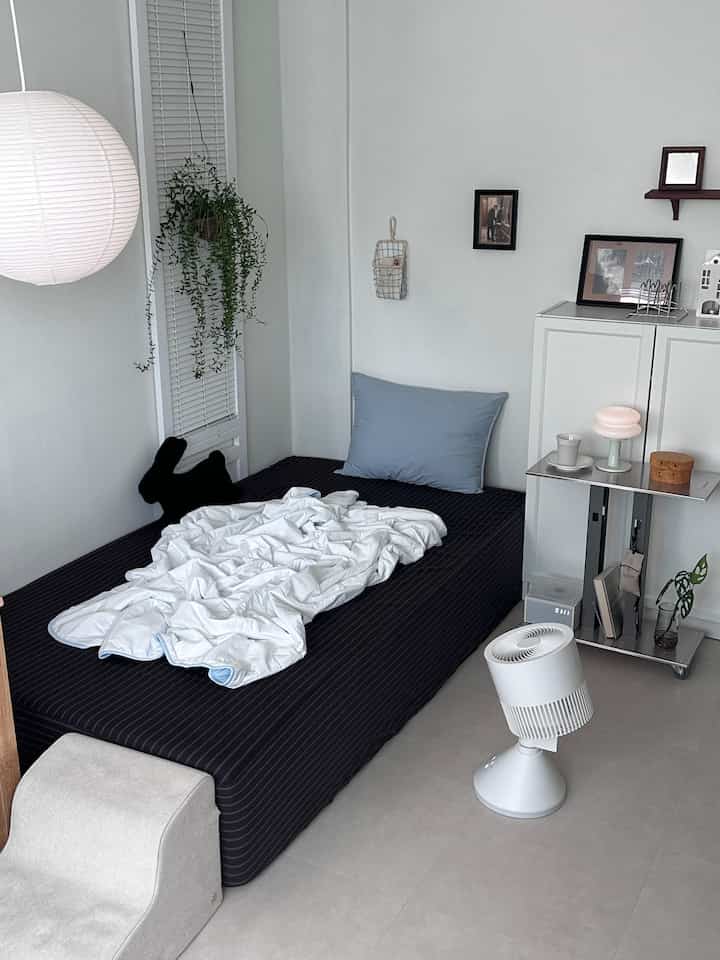 白とスカイブルーのトーンの寝室、すっきりとしたベッドとミニマルな家具が配置された落ち着いた空間