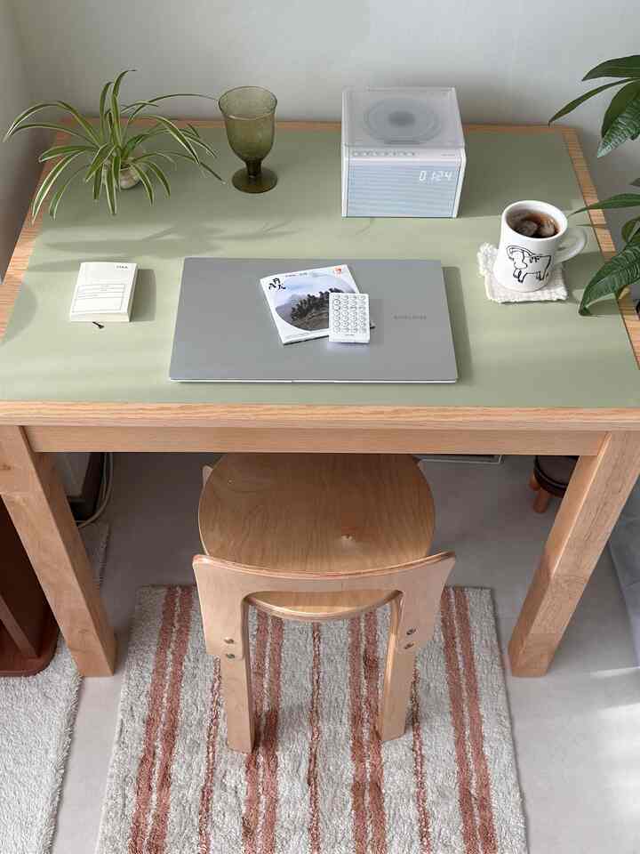 ナチュラルウッド調で淡い緑のテーブルマットが敷かれたホームオフィスデスク、清潔で温かみのある雰囲気