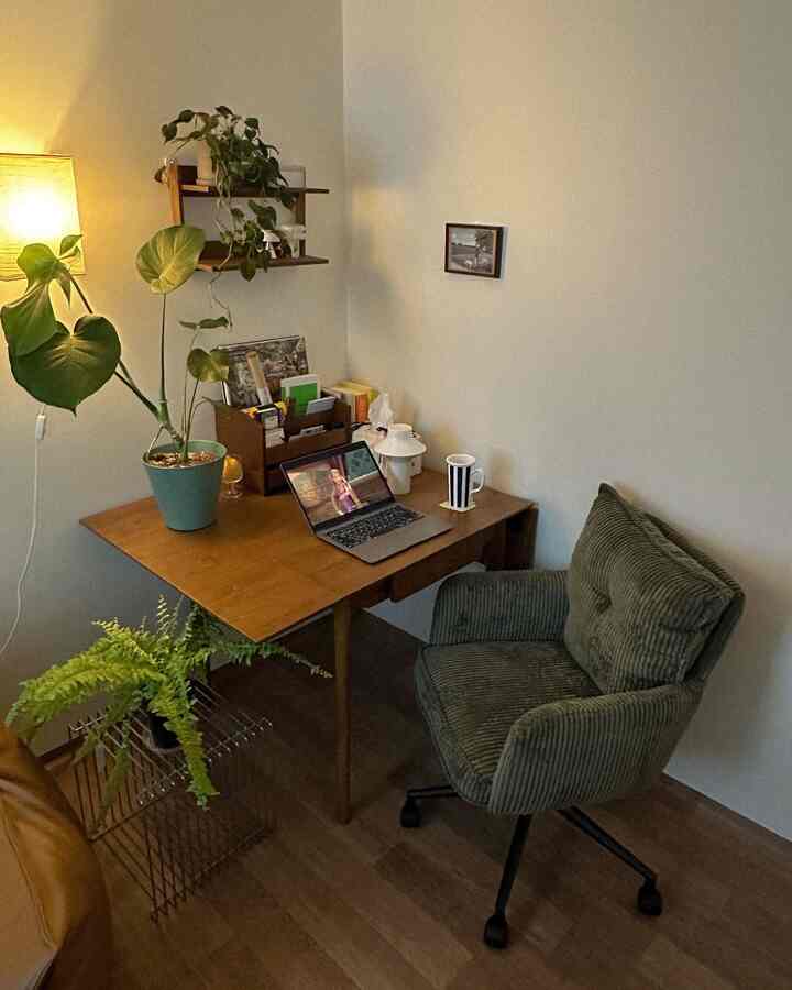 木目調と緑の色調の狭いホームオフィス、コーデュロイのオフィスチェアと植物が配置された雰囲気のあるインテリア