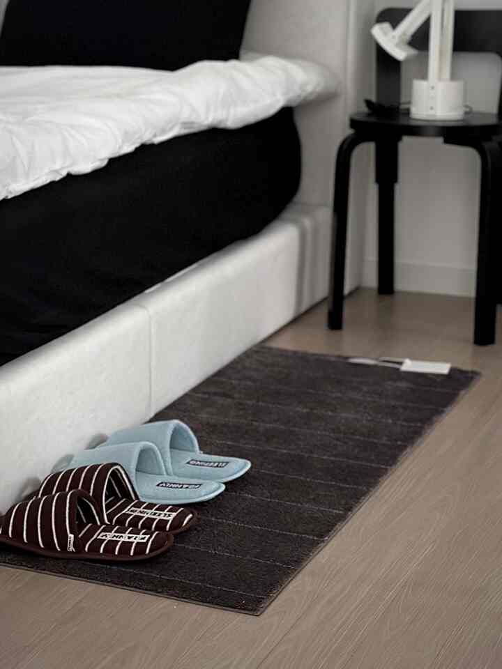 ブラウンとブルーのルームスリッパが置かれたナチュラル調の寝室、マットとベッドが配置された落ち着いた雰囲気のインテリア