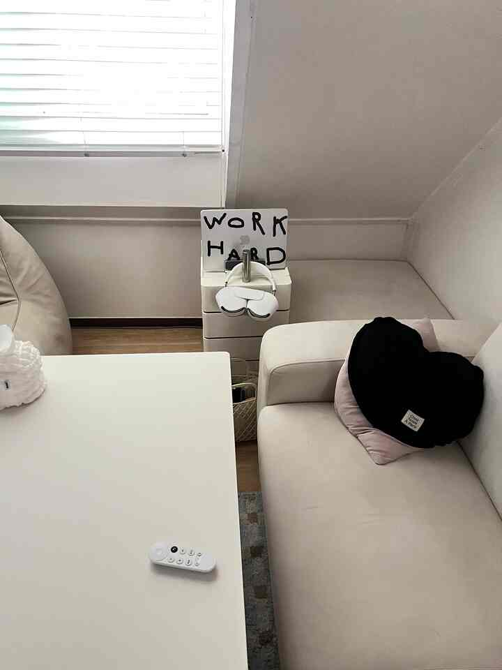 白とベージュの色調のリビング、ソファとテーブルが配置され、窓際に『WORK HARD』のサインが置かれている雰囲気のあるインテリア
