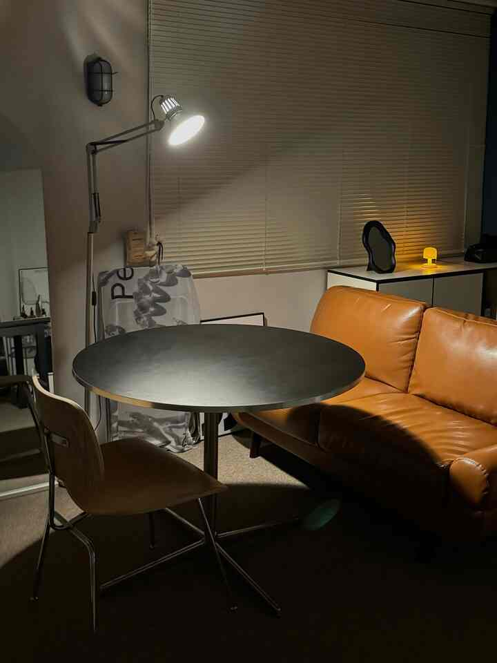 Warm brown leather sofa and black round dining table in a living room with accent lighting