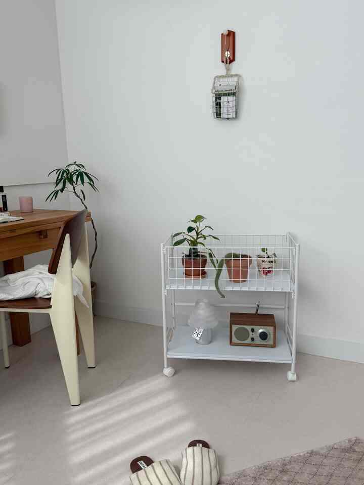 Clean home office space with white walls and floor, wooden dining table and cream chairs arranged neatly