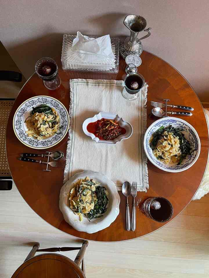 温かみのある木目調のダイニングテーブルにヴィンテージ風のパスタと飲み物が配置された印象的なホームパーティースペース