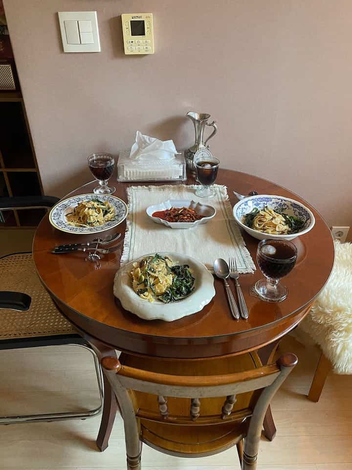 ブラウンカラーのダイニングルーム、丸いテーブルに4人分の食事皿とグラスが配置された雰囲気のある空間