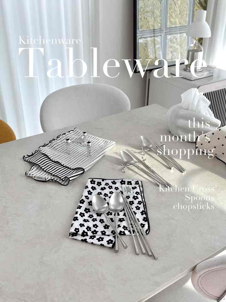 白と黒のパターンのキッチンクロスとマットなカトラリーがセラミック製のダイニングテーブルに置かれたモダンなキッチンスペース