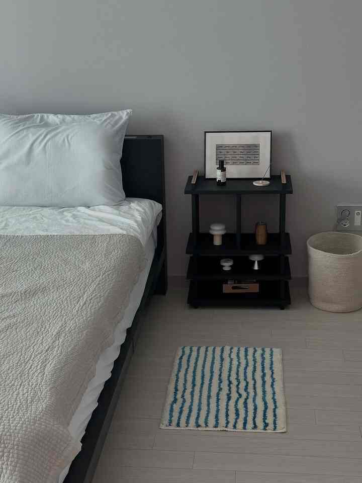 Charcoal and ivory toned bedroom with black bed frame and nightstand, featuring a clean, minimal atmosphere