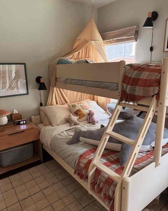 White-walled kids' room with wood-tone furniture featuring a cozy bunk bed and wall sconces in a warm atmosphere