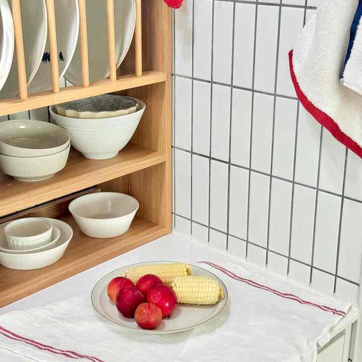 白と木目調を基調としたキッチン、皿とタオルが配置された清潔感ある印象の空間