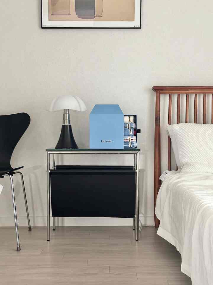 白と黒の調和が美しいモダンな寝室、木製ベッドとブルーのコトナタオルセットがナイトテーブルに置かれた清潔感のあるインテリア