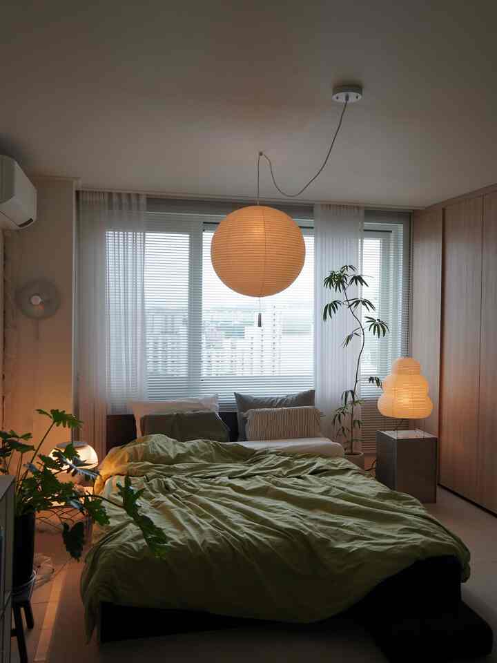 柔らかいホワイトと木目調、緑の植物が調和したミッドセンチュリーモダンの寝室