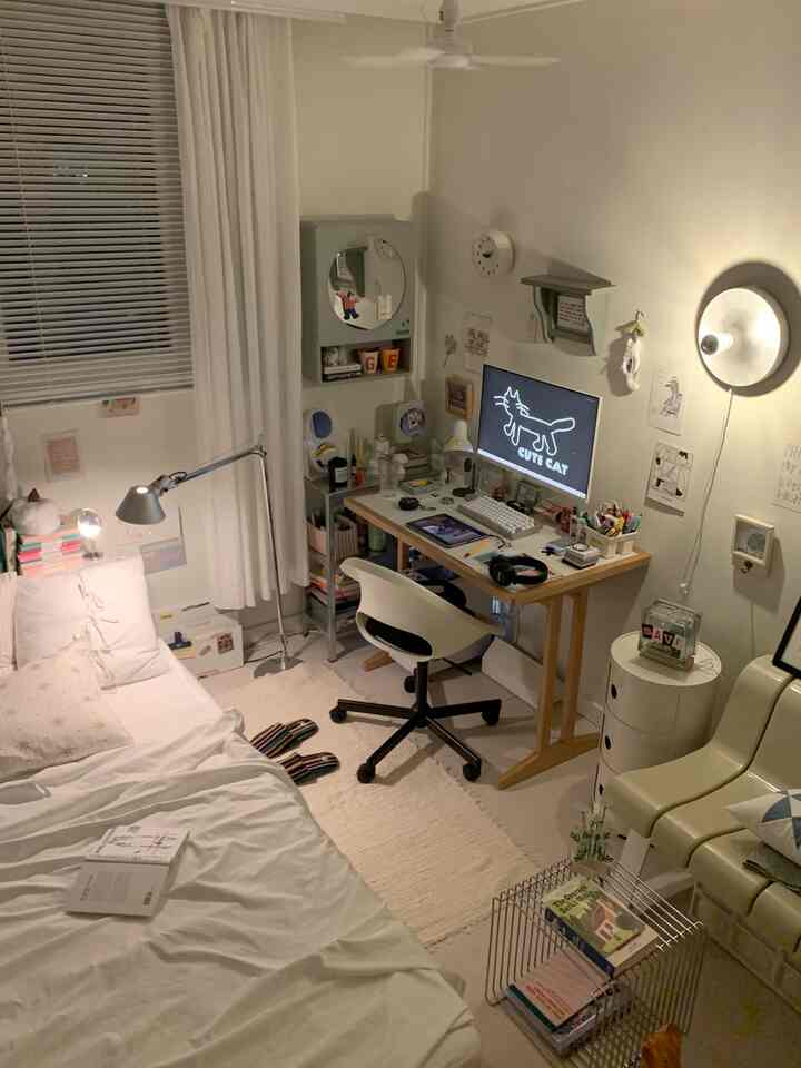 White and natural modern toned compact bedroom featuring a desk, bookshelf, and computer monitor creating a cozy and practical home office