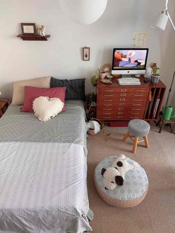 ナチュラルな色調の寝室、木製家具と植物、犬の形のクッションが配置された雰囲気のあるインテリア