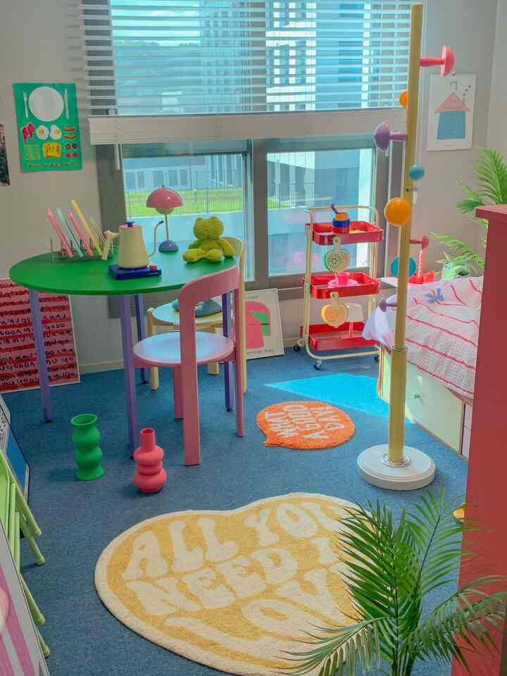 涼しげなブルーのタイルカーペットとパステル調の家具が配置された明るくかわいらしい子供部屋のインテリア