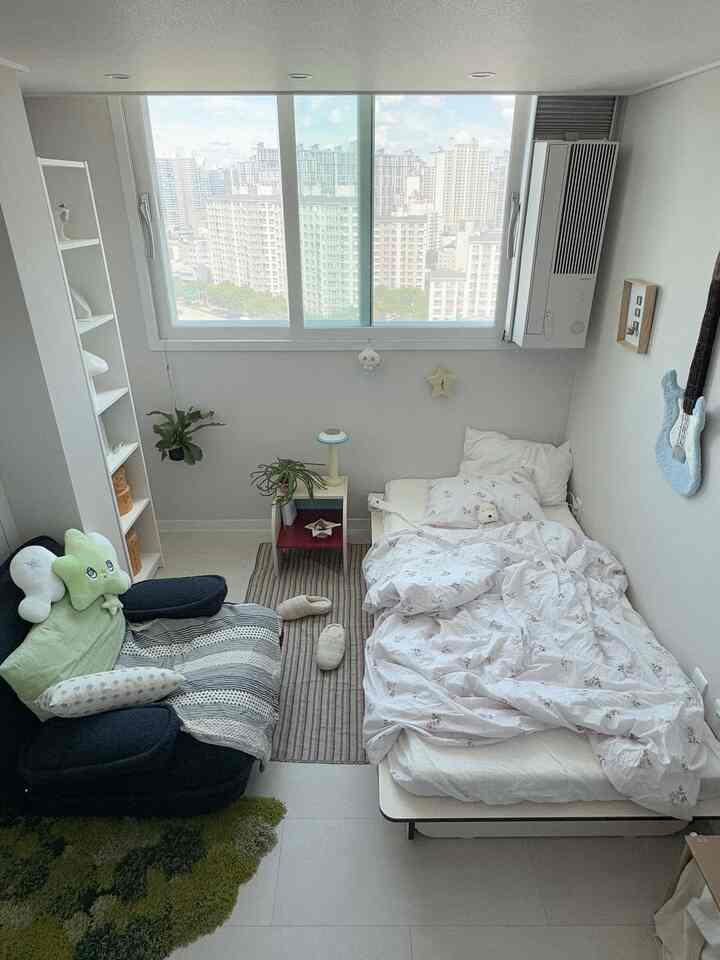 ホワイトトーンのワンルーム寝室、左にソファ、右にベッドが配置された落ち着いた雰囲気のあるインテリア