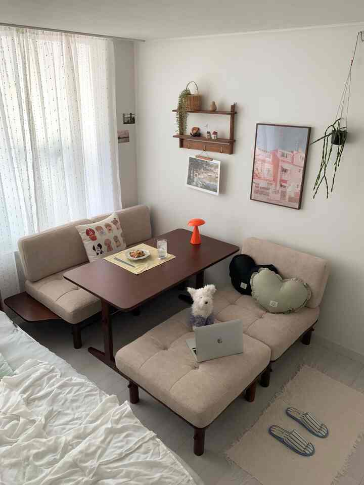 ベージュとブラウンの色調の小さなワンルームリビング、ソファとダイニングテーブルが配置された落ち着いた雰囲気のあるインテリア