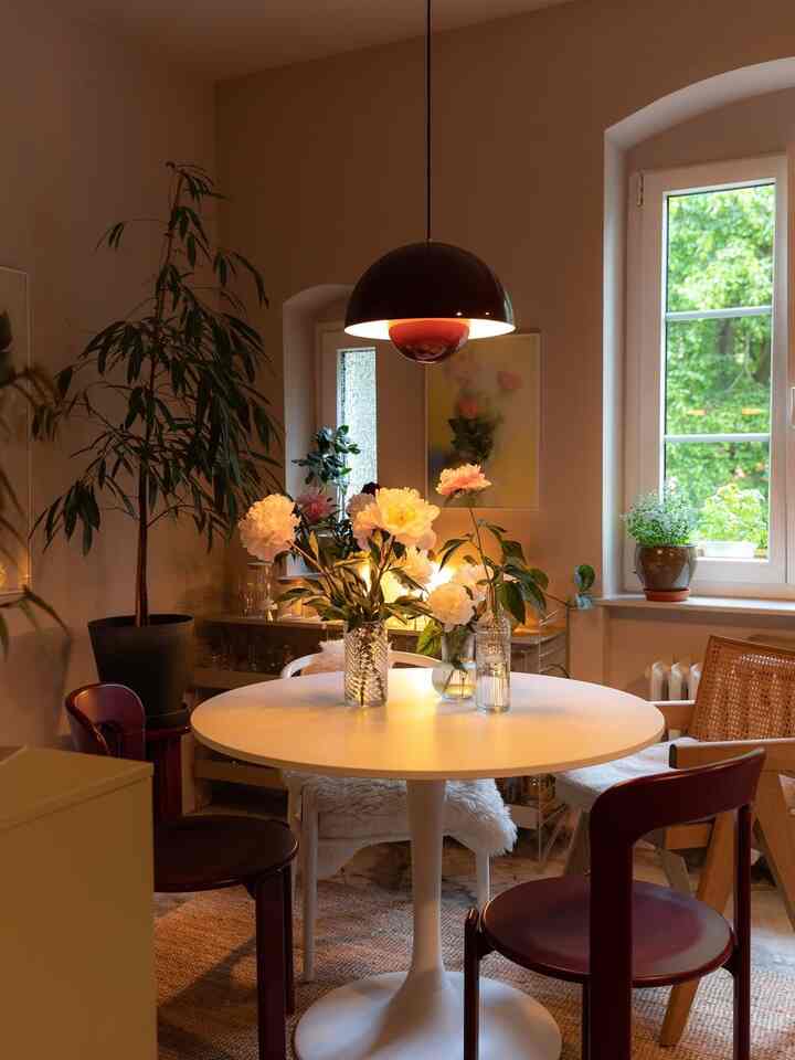 Warm beige-toned dining room featuring a round table surrounded by mixed chairs and a pendant light, creating a cozy vintage vibe