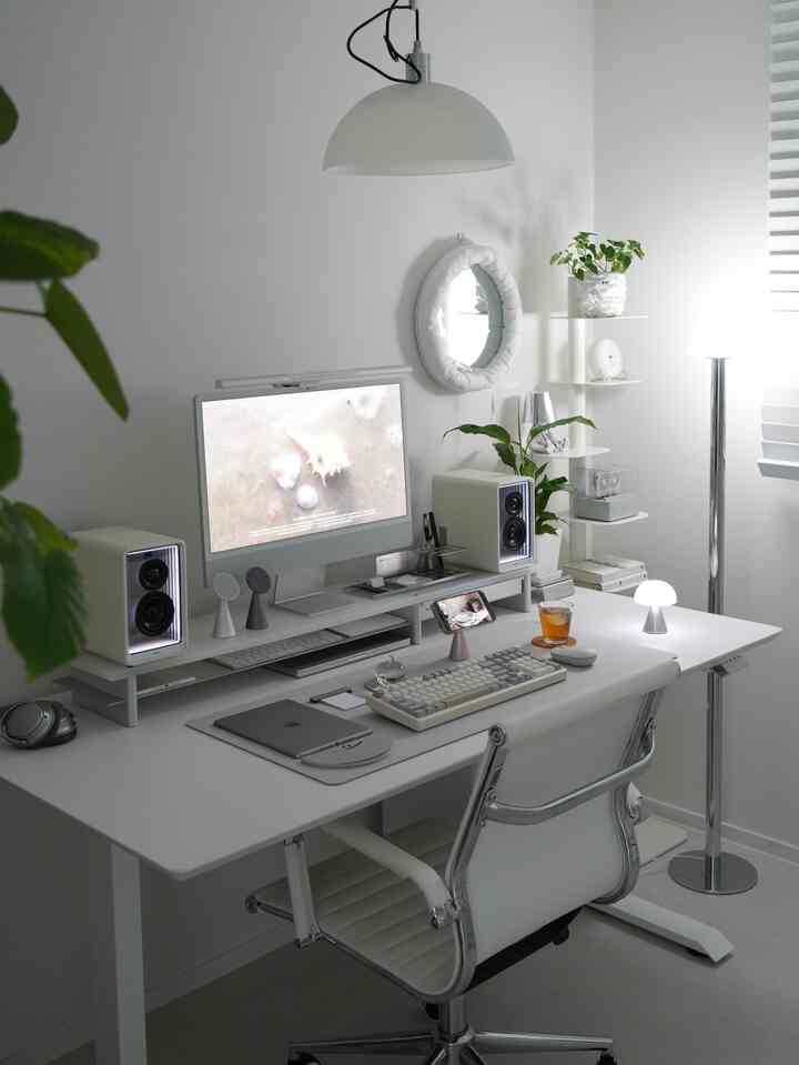 White-toned home office featuring modern desk, chair, and lighting fixtures arranged in a clean minimalist style