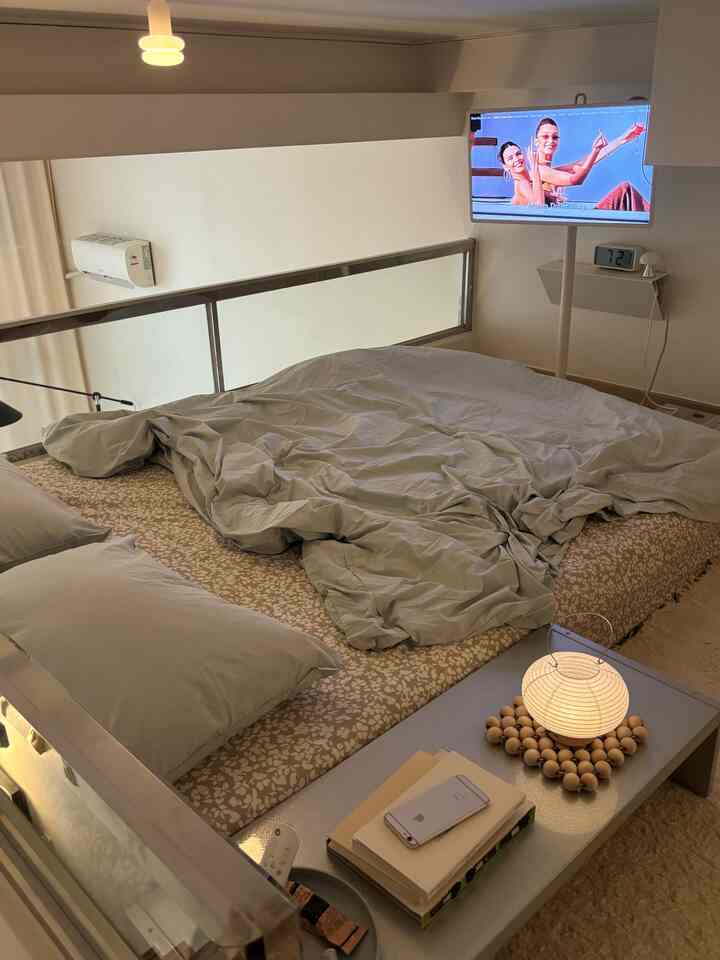 ベージュとグレーの色調の寝室、快適なベッドと小型のテーブルランプが配置されたモダンな狭い部屋