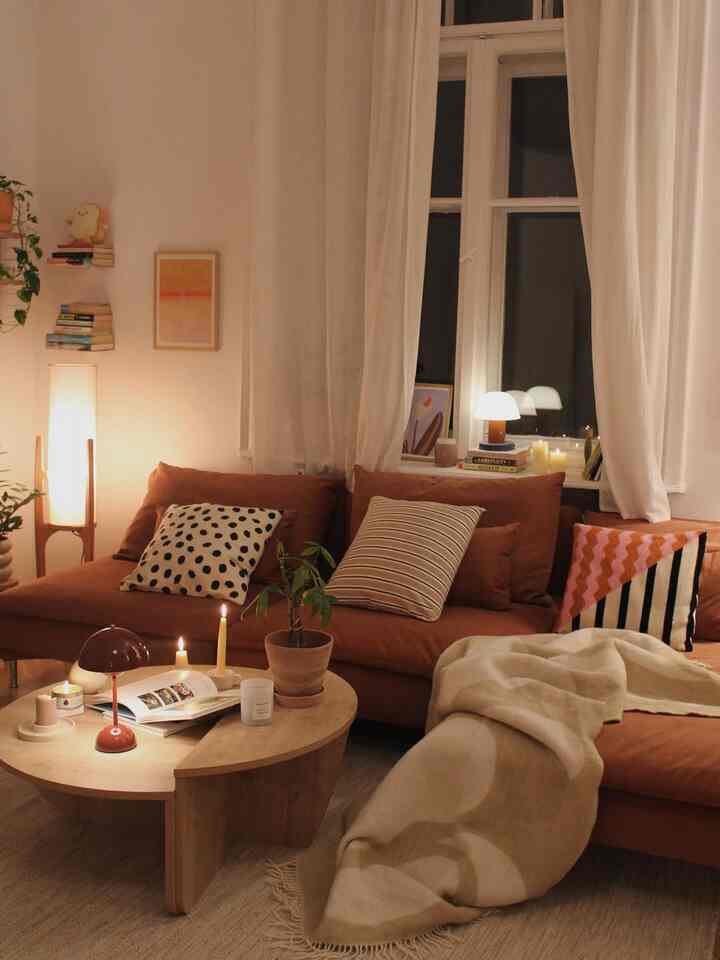 Cozy living room in warm beige and brown tones featuring a sectional sofa, natural wood coffee table, and soft warm lighting
