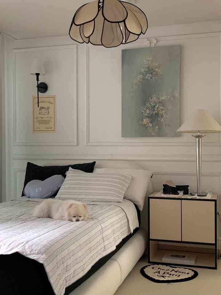 白と黒のモノトーンの寝室、中央にベッドと枕が配置され、愛らしいペットがくつろぐ印象的な空間