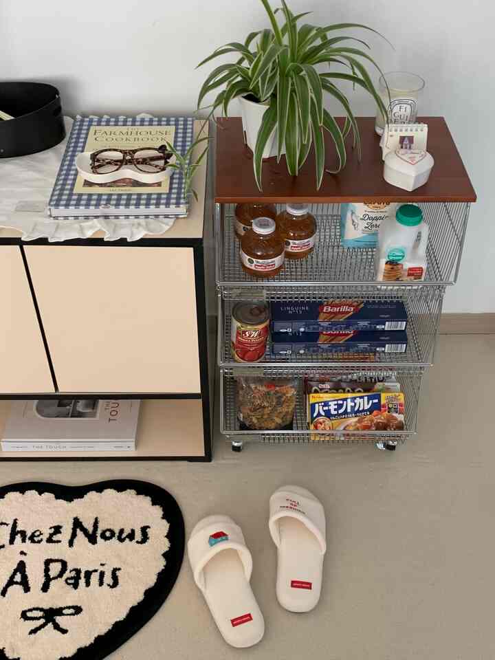 ベージュとホワイトのトーンが基調のワンルームパントリー、メタルバスケットトロリーと収納キャビネットが配置されたモダンなインテリア