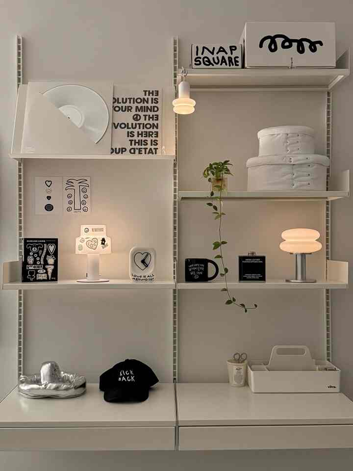 白と黒のトーンでまとめられたシンプルでナチュラルな棚の空間、アートフレームや照明、ディフューザーが配置されたモダンなインテリア