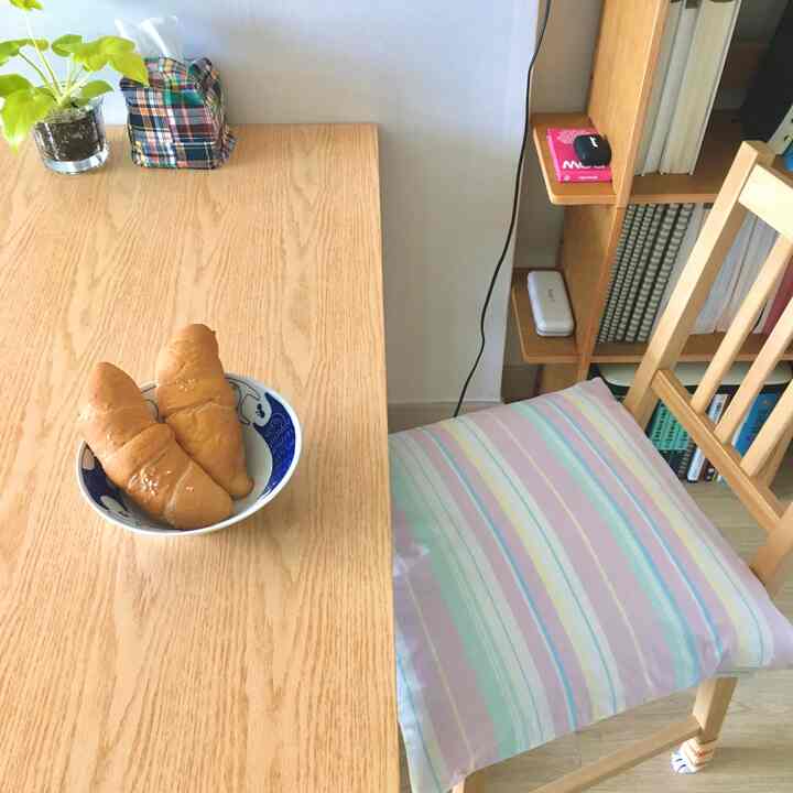 ナチュラルカラーのダイニング、木製のテーブルと椅子、ストライプのクッションが配置された雰囲気のあるインテリア