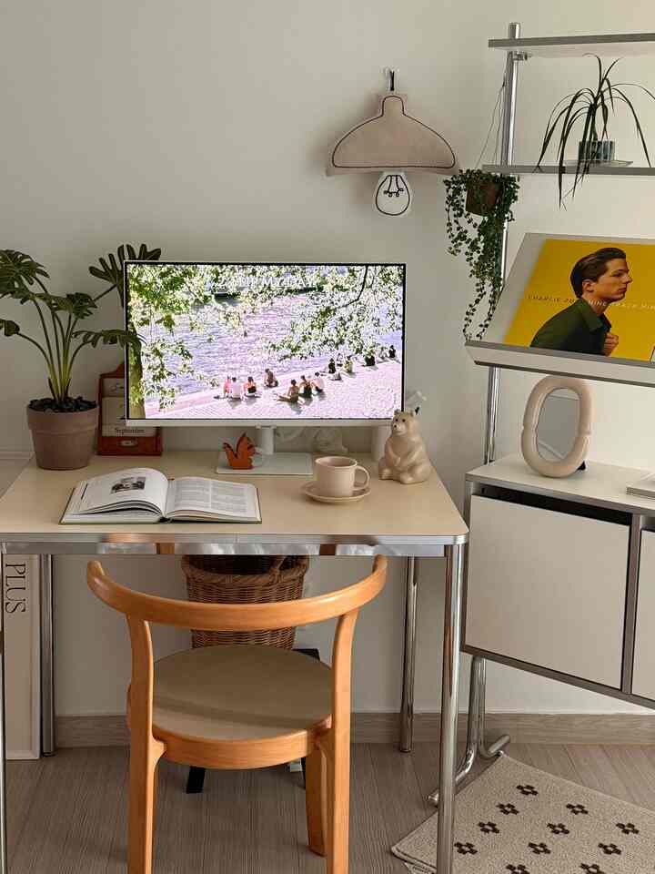 ナチュラルな色調のホームオフィス、木製の椅子とベージュのデスク、モニターと植物が配置された印象的な作業空間